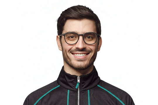 Smiling man in stylish eyewear wearing a black zip-up tracksuit jacket with teal stripes, showcasing trendy men's athletic apparel.