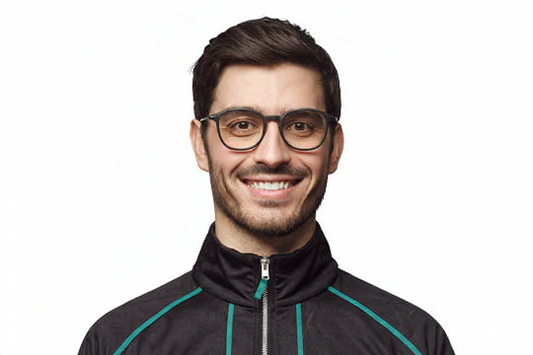 Smiling man in stylish eyewear wearing a black zip-up tracksuit jacket with teal stripes, showcasing trendy men's athletic apparel.